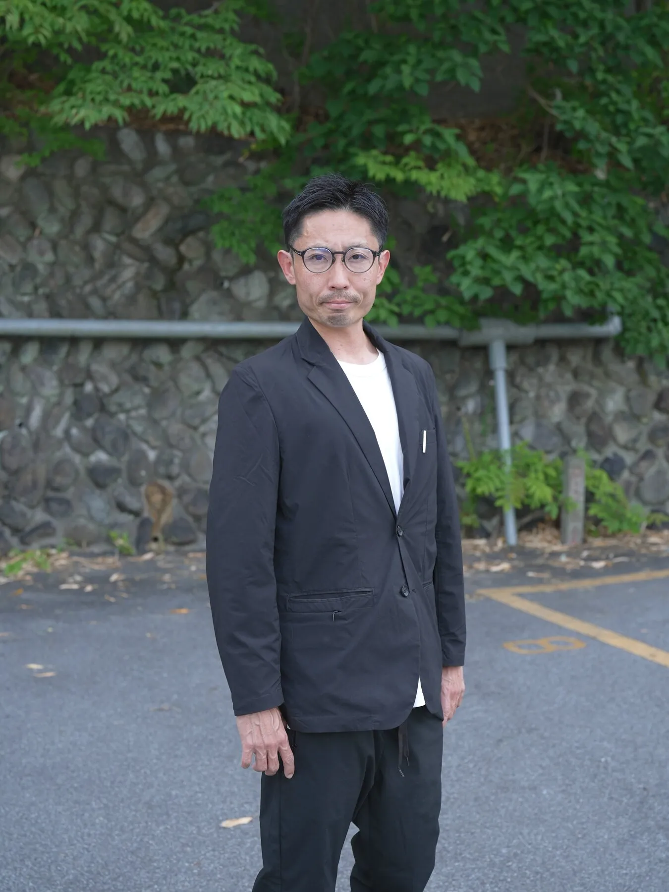 緑の壁の前に立つ篠原さん