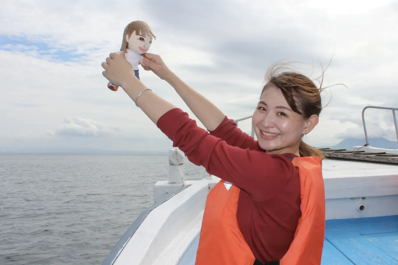 船の上でぬいぐるみを掲げる義川さん